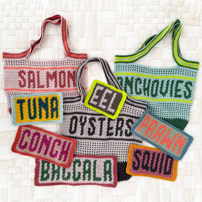 Crocheted tote bags and fish-themed patches on a textured white background
