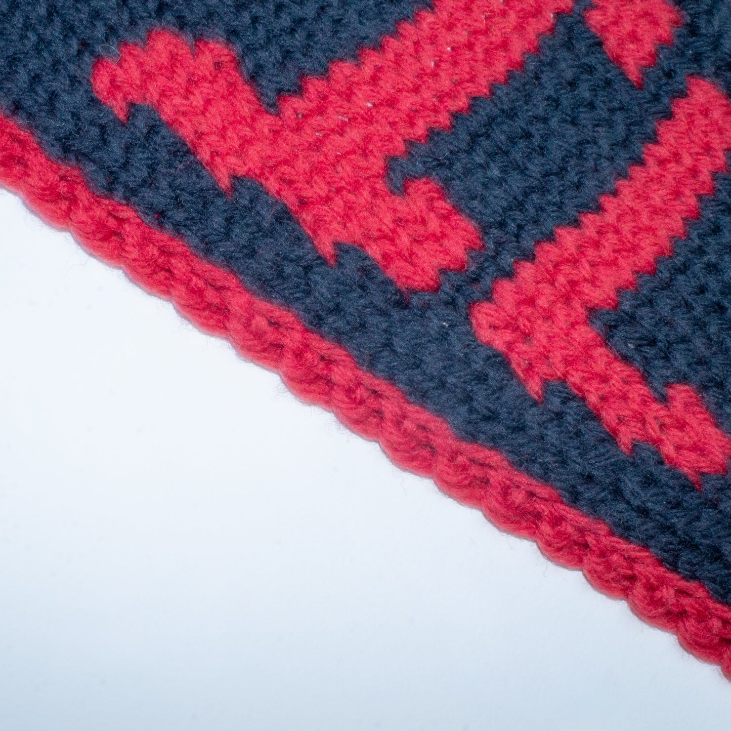 Close-up of a red and black knit pennant with a graphic design containing the word "DEVIL"