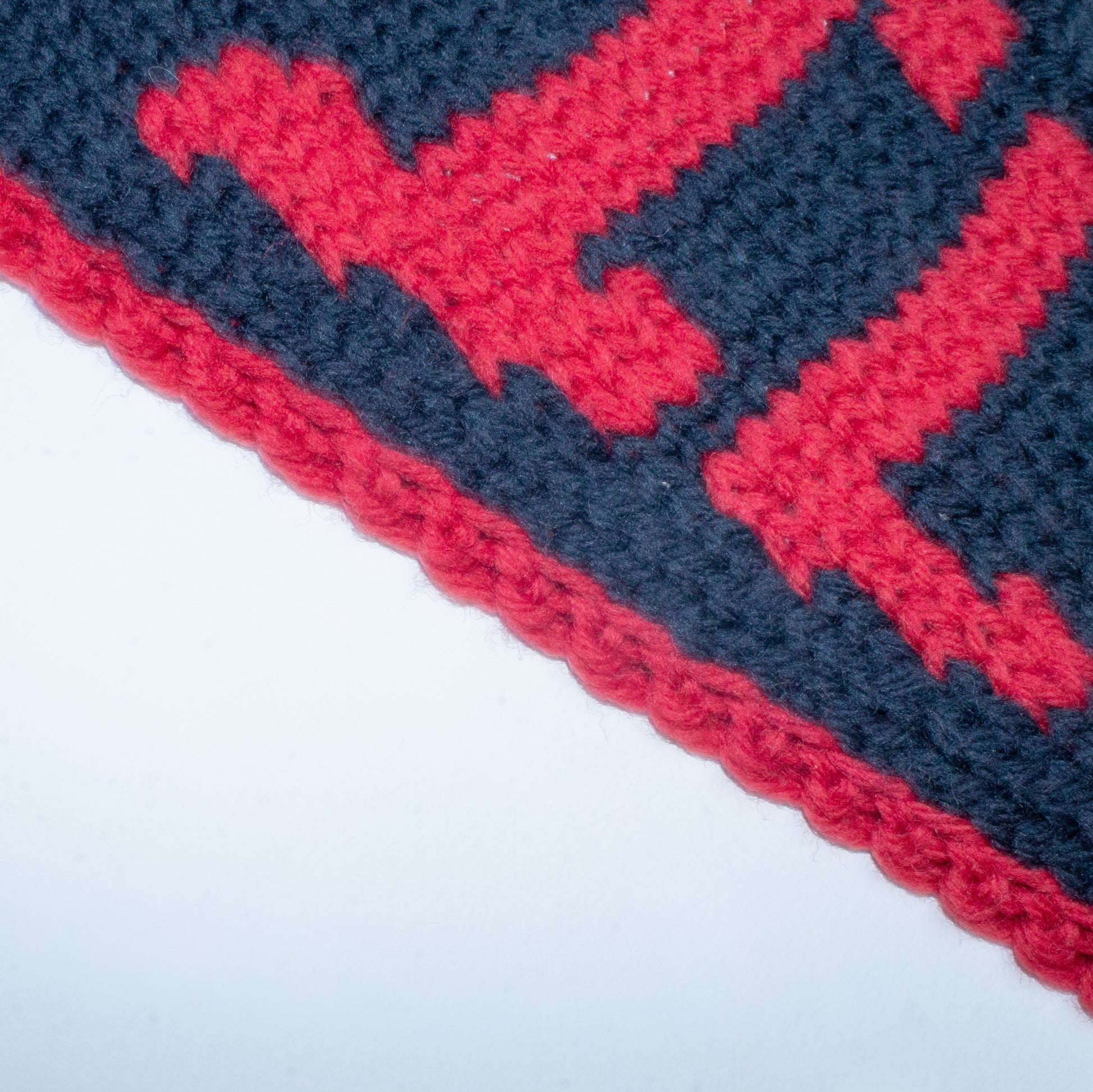 Close-up of a red and black knit pennant with a graphic design containing the word "DEVIL"