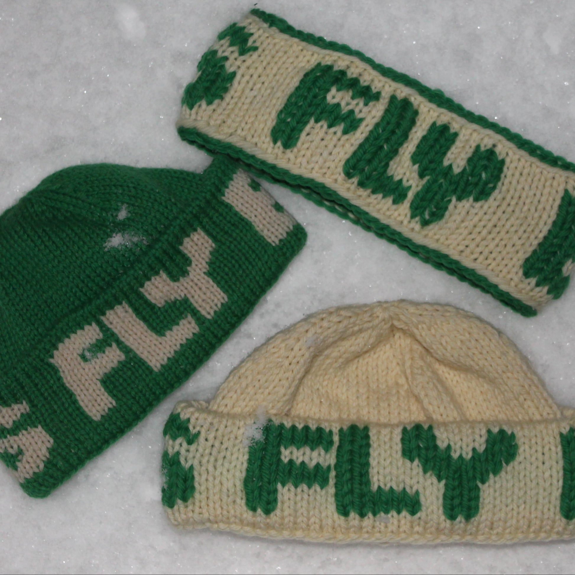Two beanies and one ear warmer all with the word FLY in the colors kelly green and white