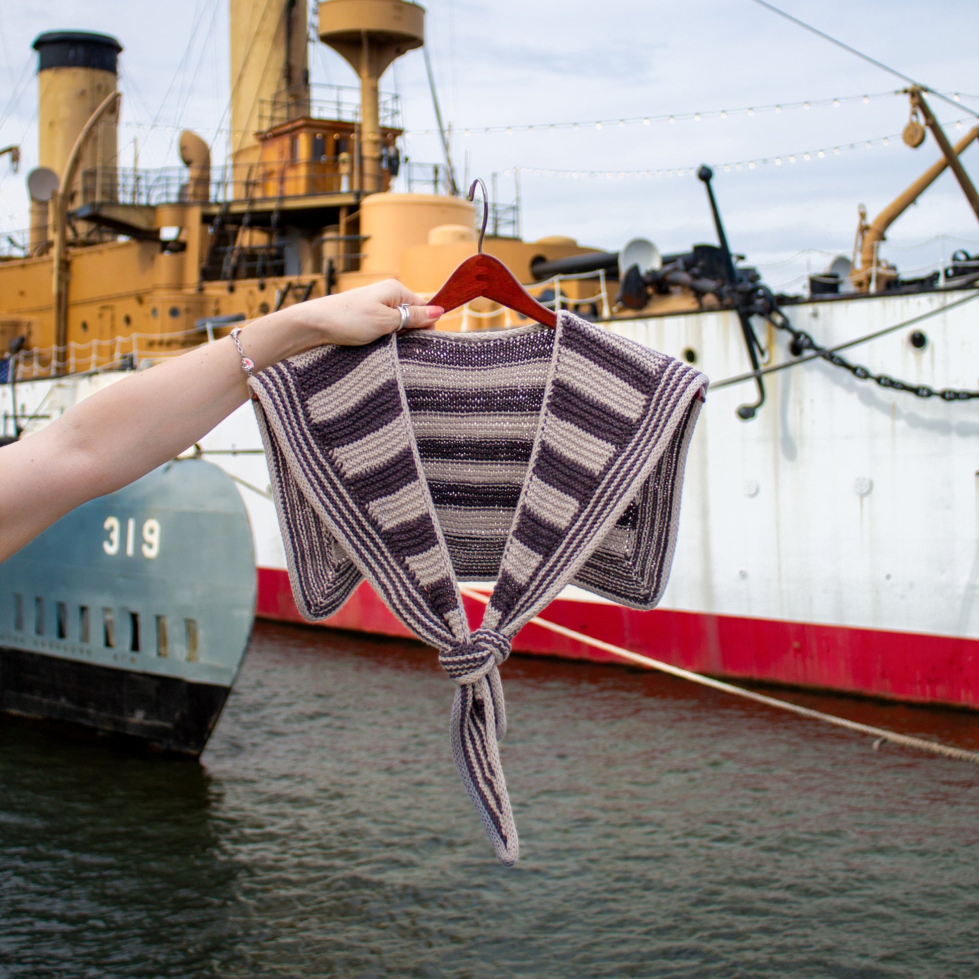Knitted striped sailor scarf on a hanger with a large ship in the background